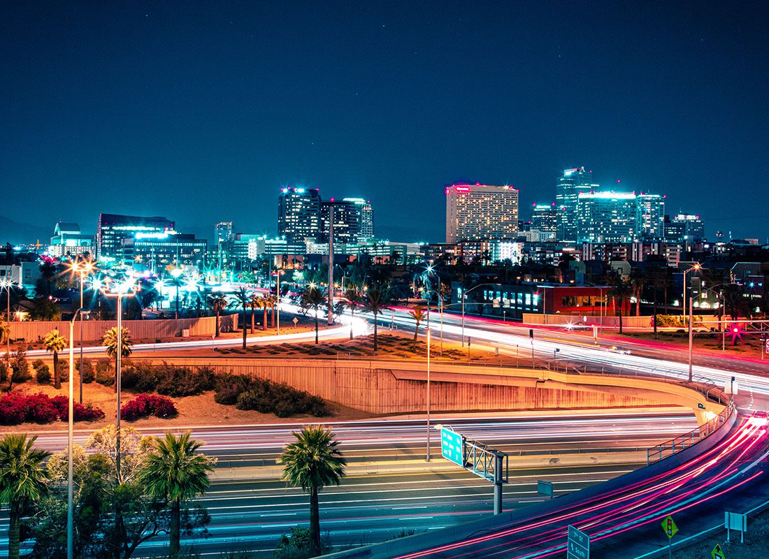 Contact - Nighttime View of Phoenix, Arizona Displaying Bright Business Buildings and Blurred Cars Moving on a Highway
